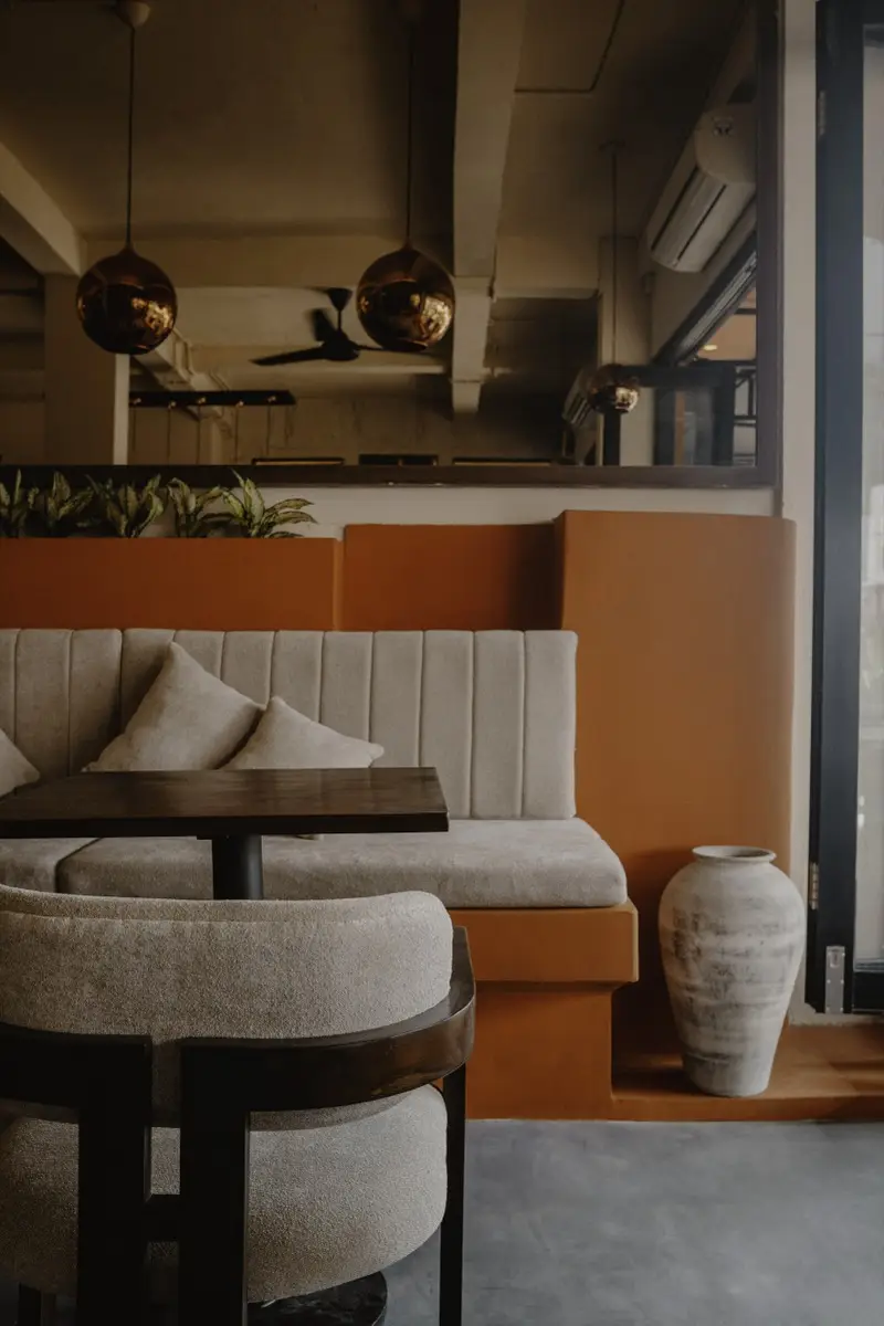 Cream booth against a terracotta wall with a clay vase