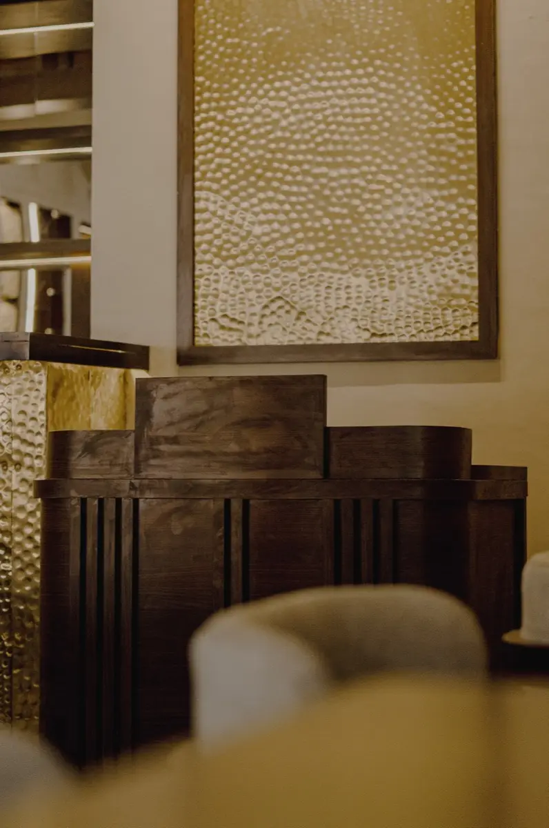 Hammered brass artwork above a dark wood bar cabinet