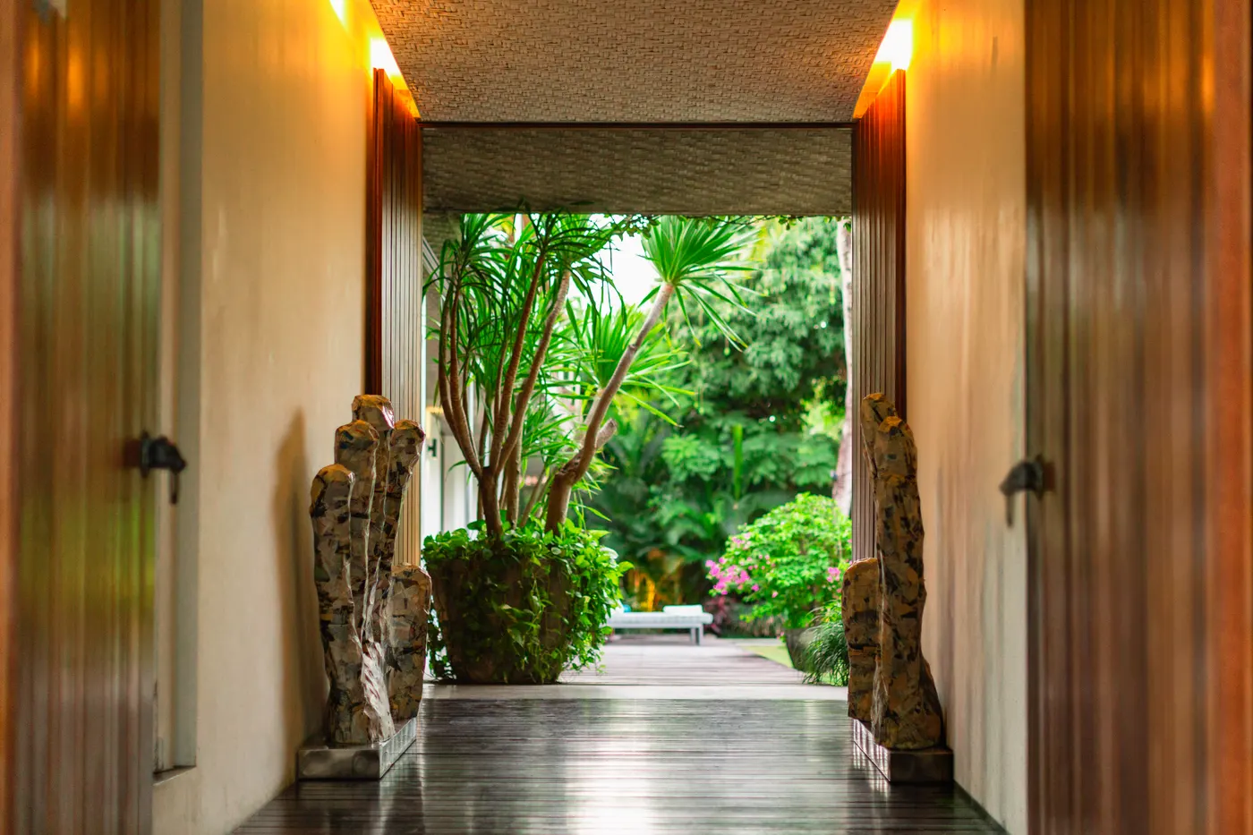 Sunlit walkway between carved stone guardians into the garden
