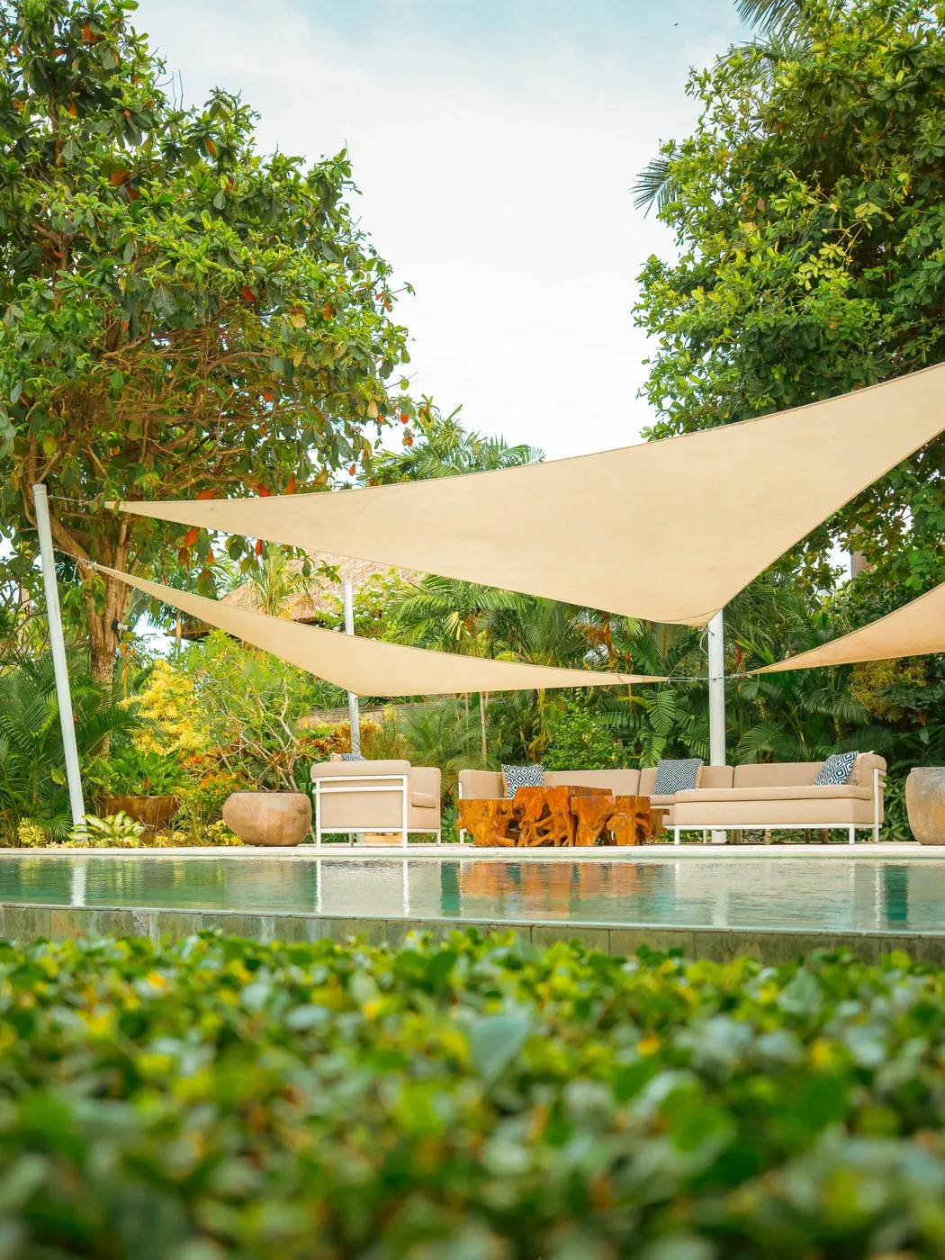 Cream sail shades over loungers beside the pool