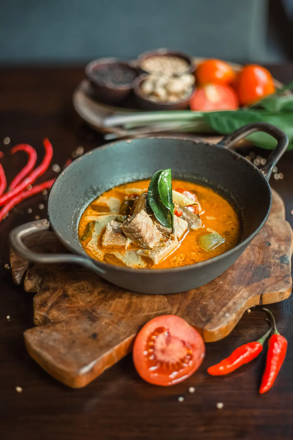 Fish curry in a cast iron pan with chillies and tomato