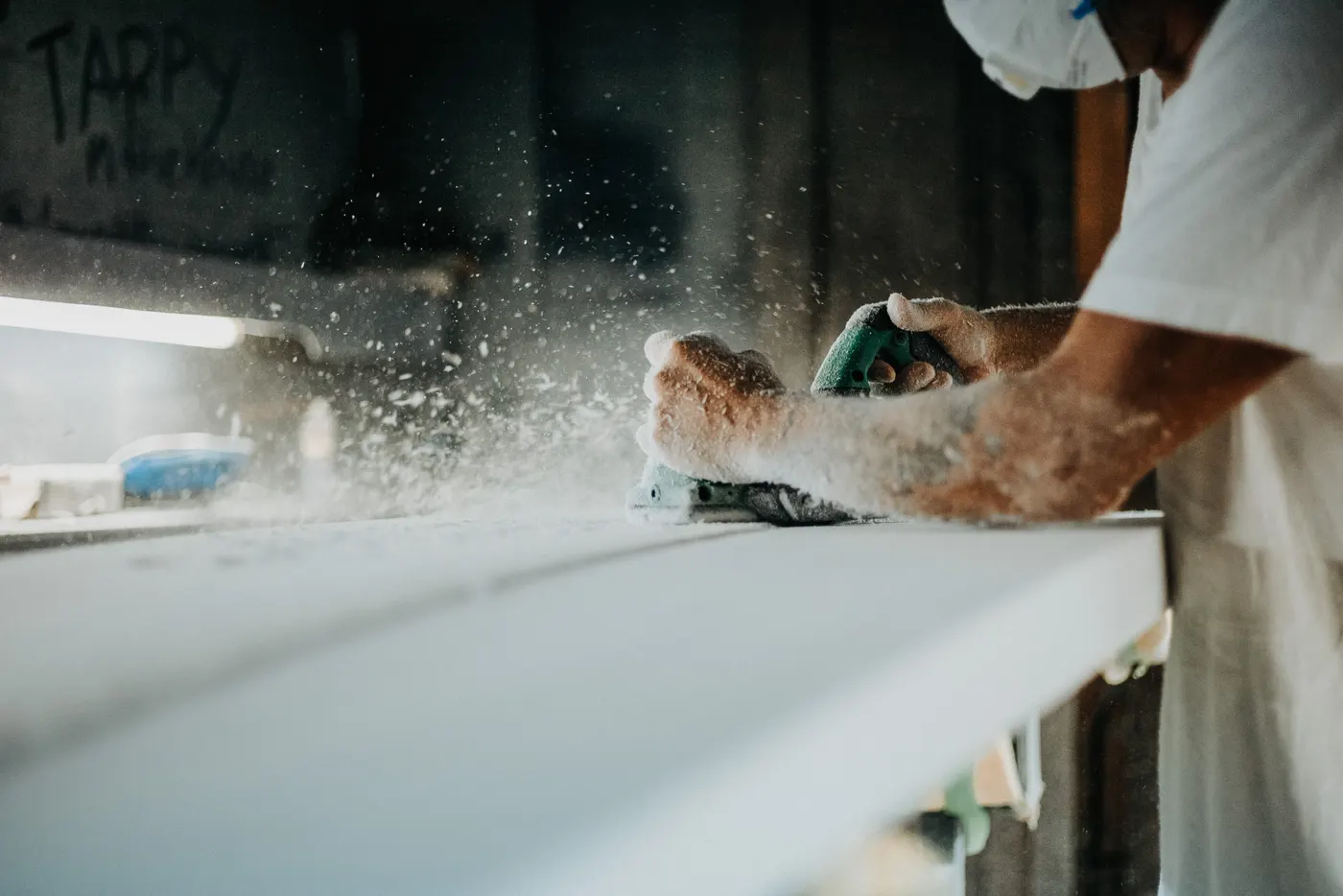 Sanding dust flying off a surfboard
