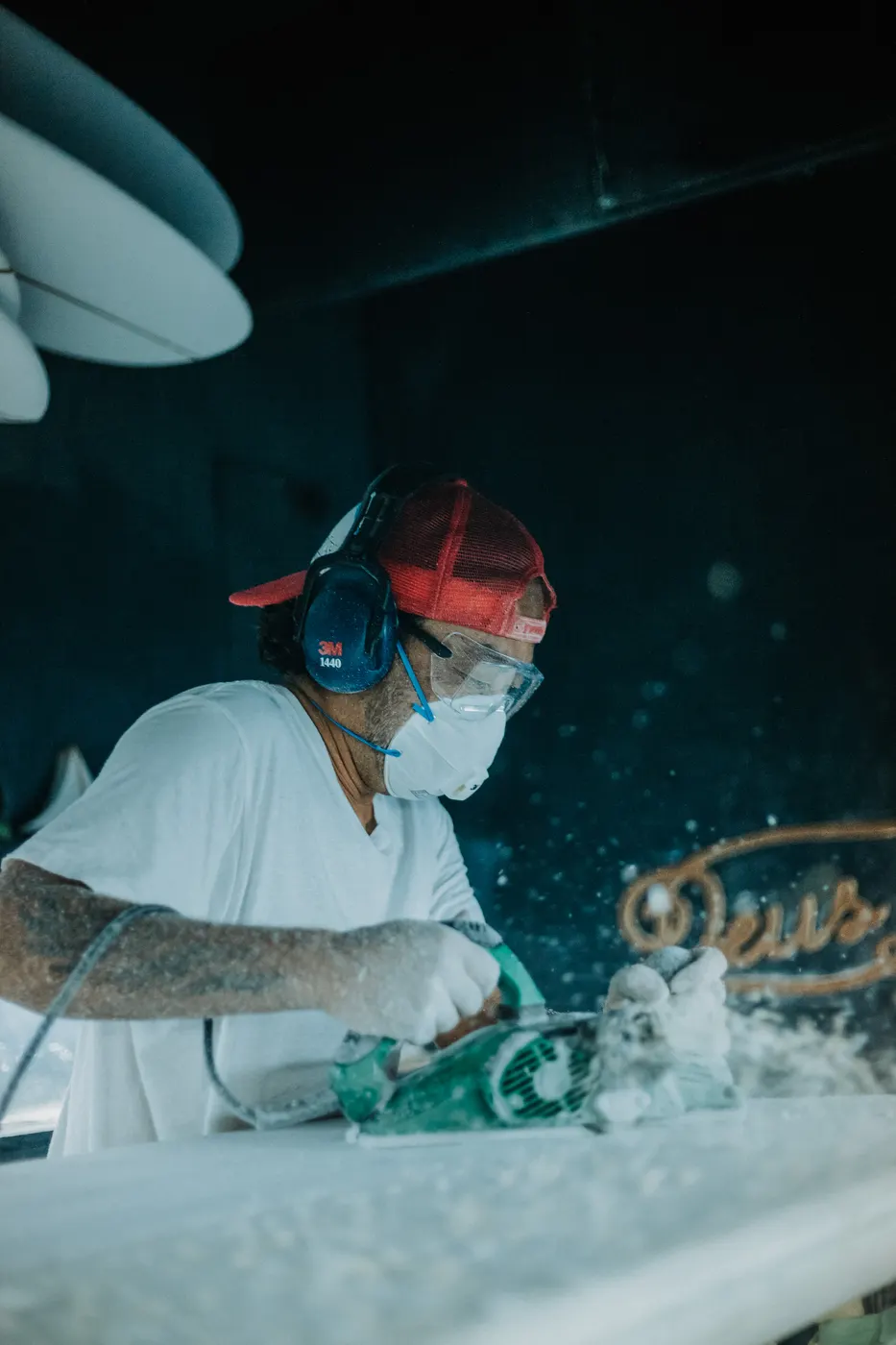 Shaper in a red cap spraying a board